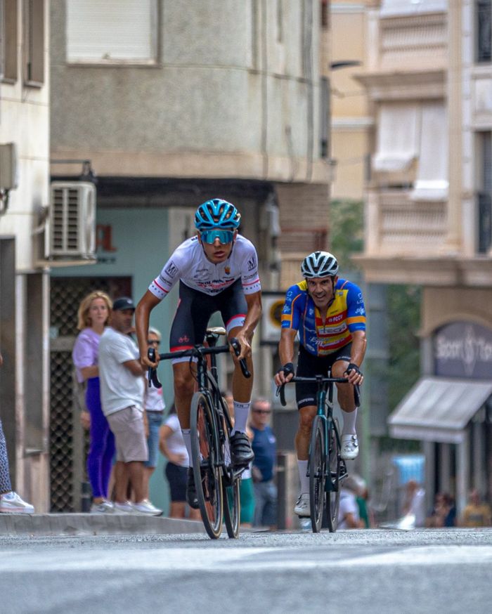 Two cyclists racing through the streets of Valencia, showcasing speed and athleticism.